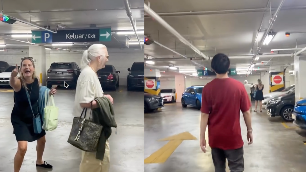 Two people standing in a Kuala Lumpur parking spot during a dispute as a Malaysian couple approaches them.